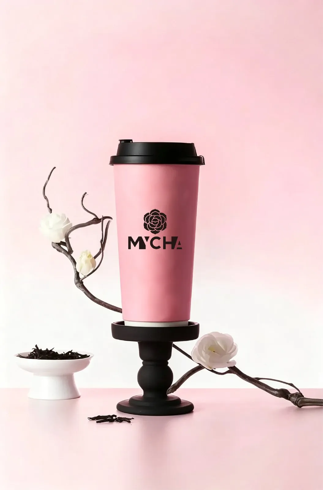 A pink MYCHA cup on a dark pedestal beside a camellia branch