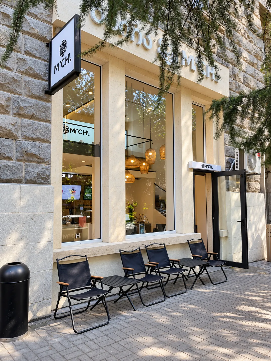 MYCHA storefront with tall windows, a stone facade and outdoor seating