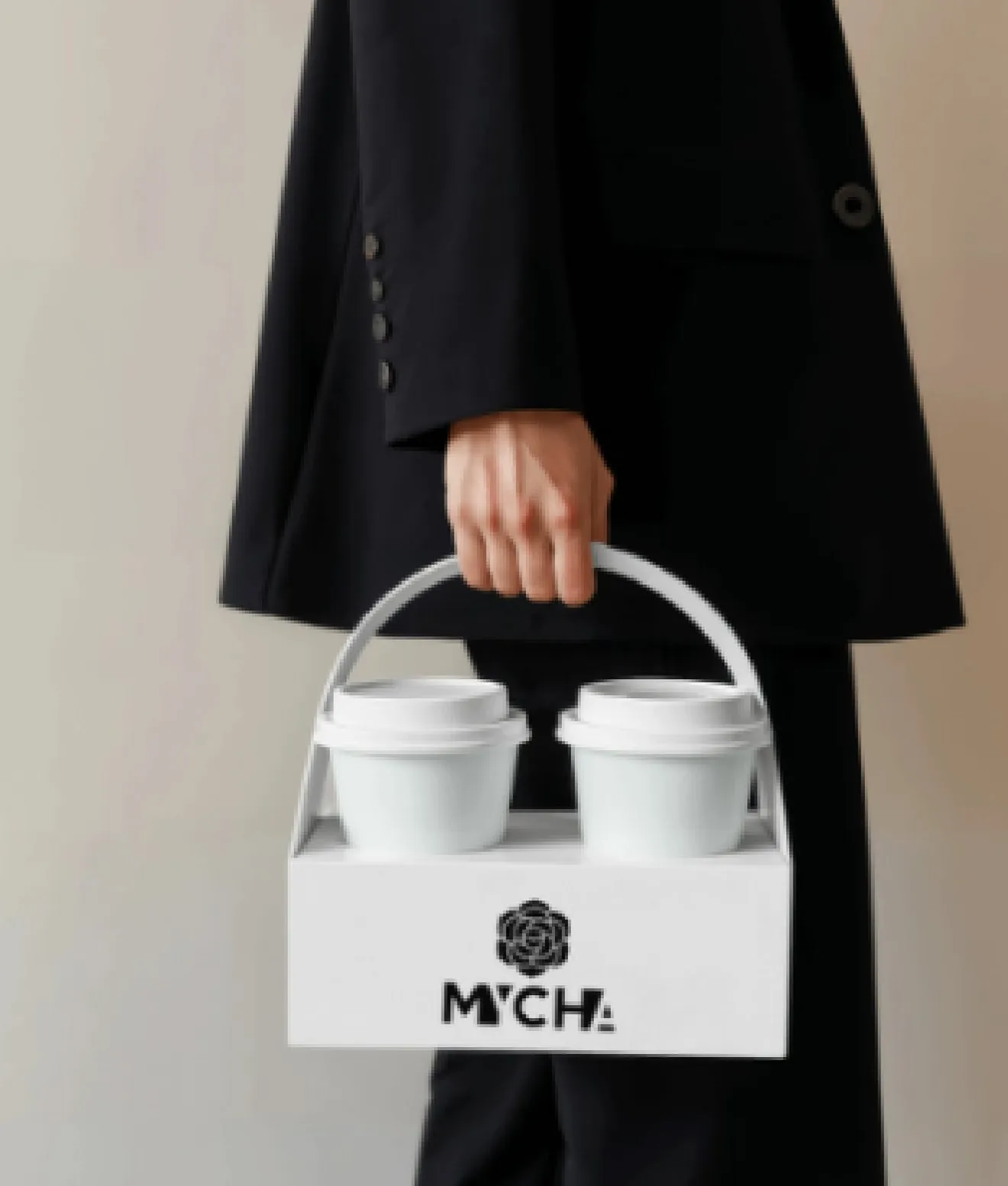 A white MYCHA two-cup carrier held at a woman's side