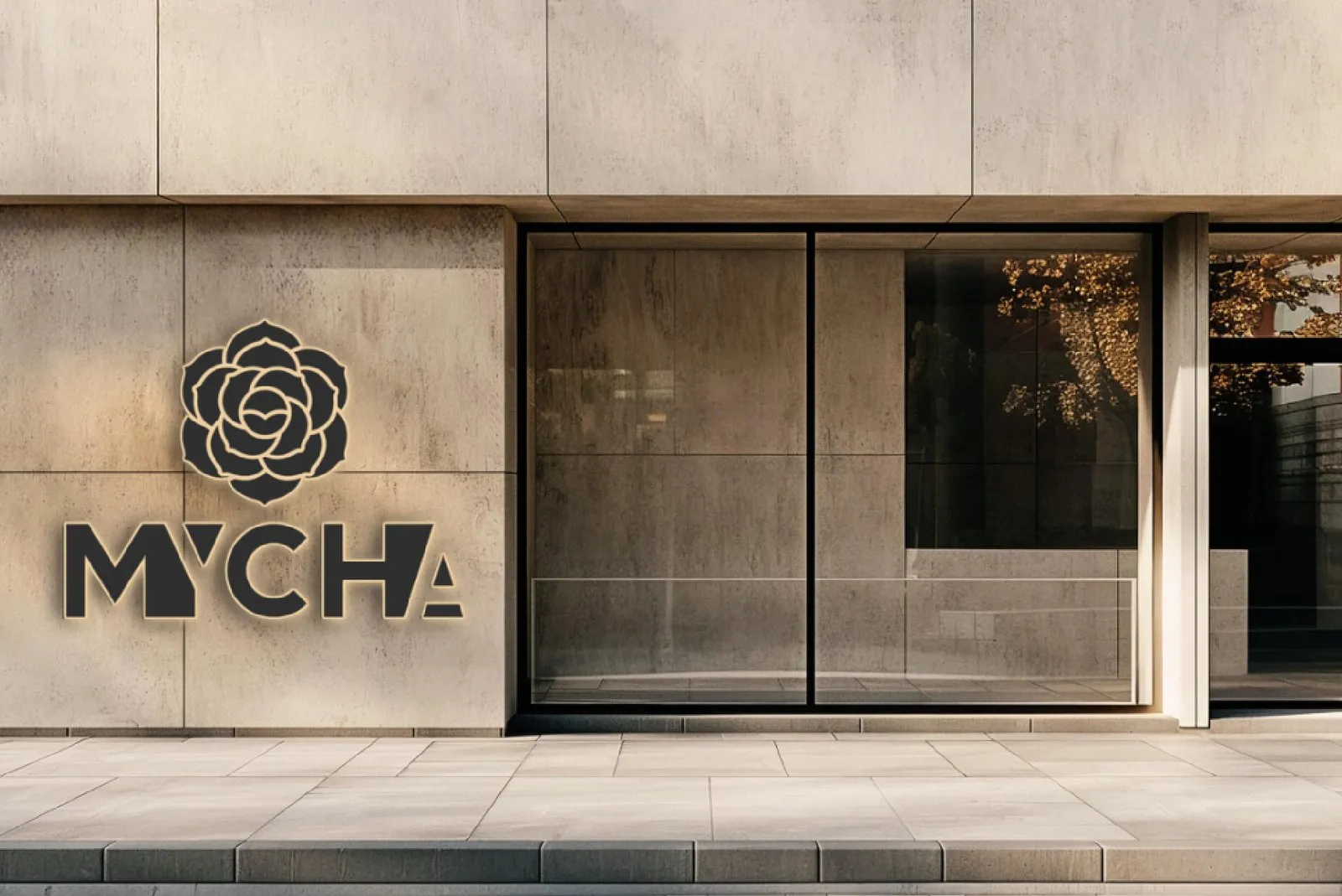 A fair-faced concrete MYCHA storefront with the camellia logo in relief