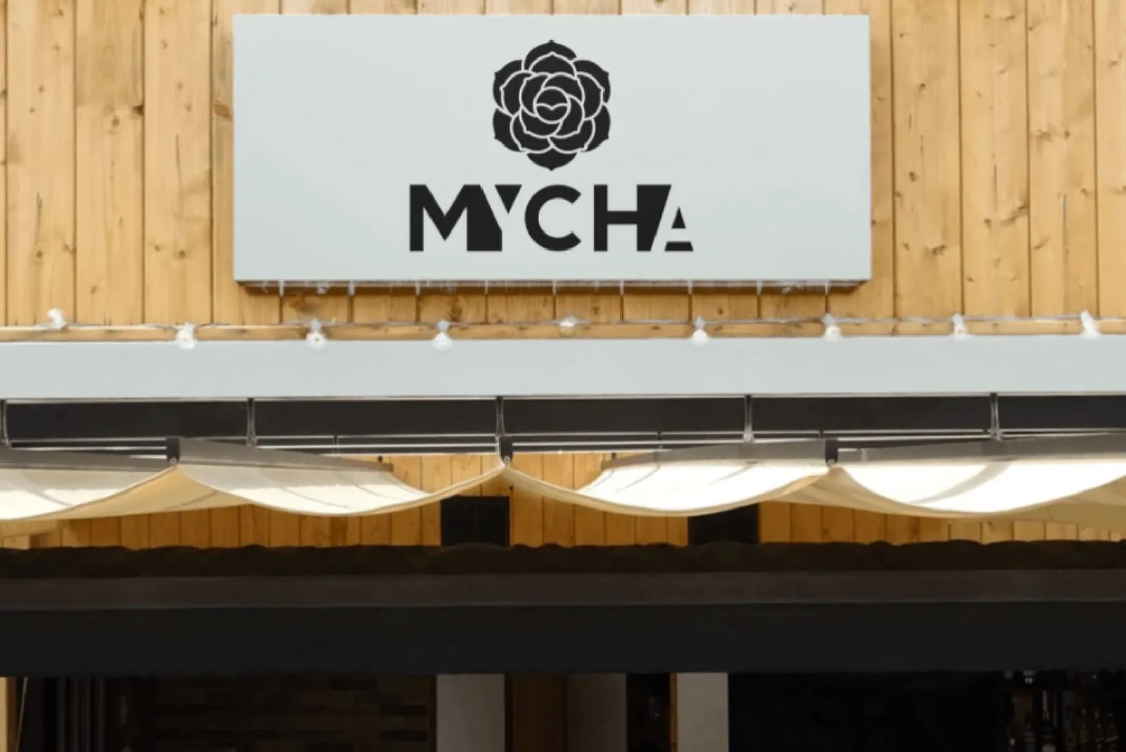 A MYCHA storefront of natural wooden planks with a white sign
