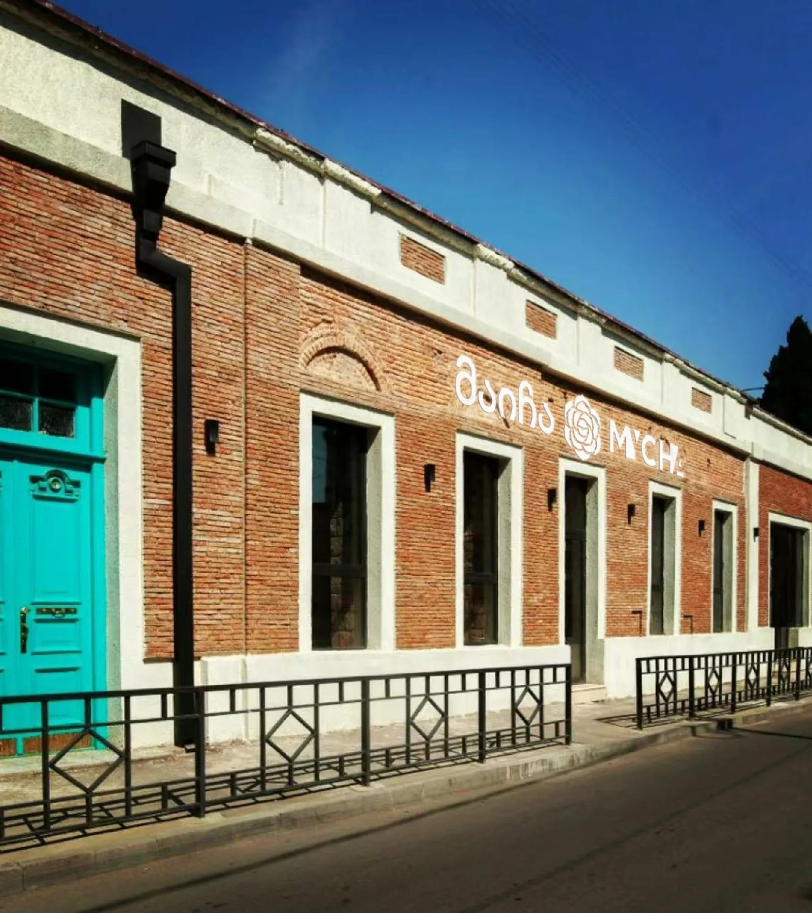 MYCHA Tbilisi's red-brick facade with a turquoise door