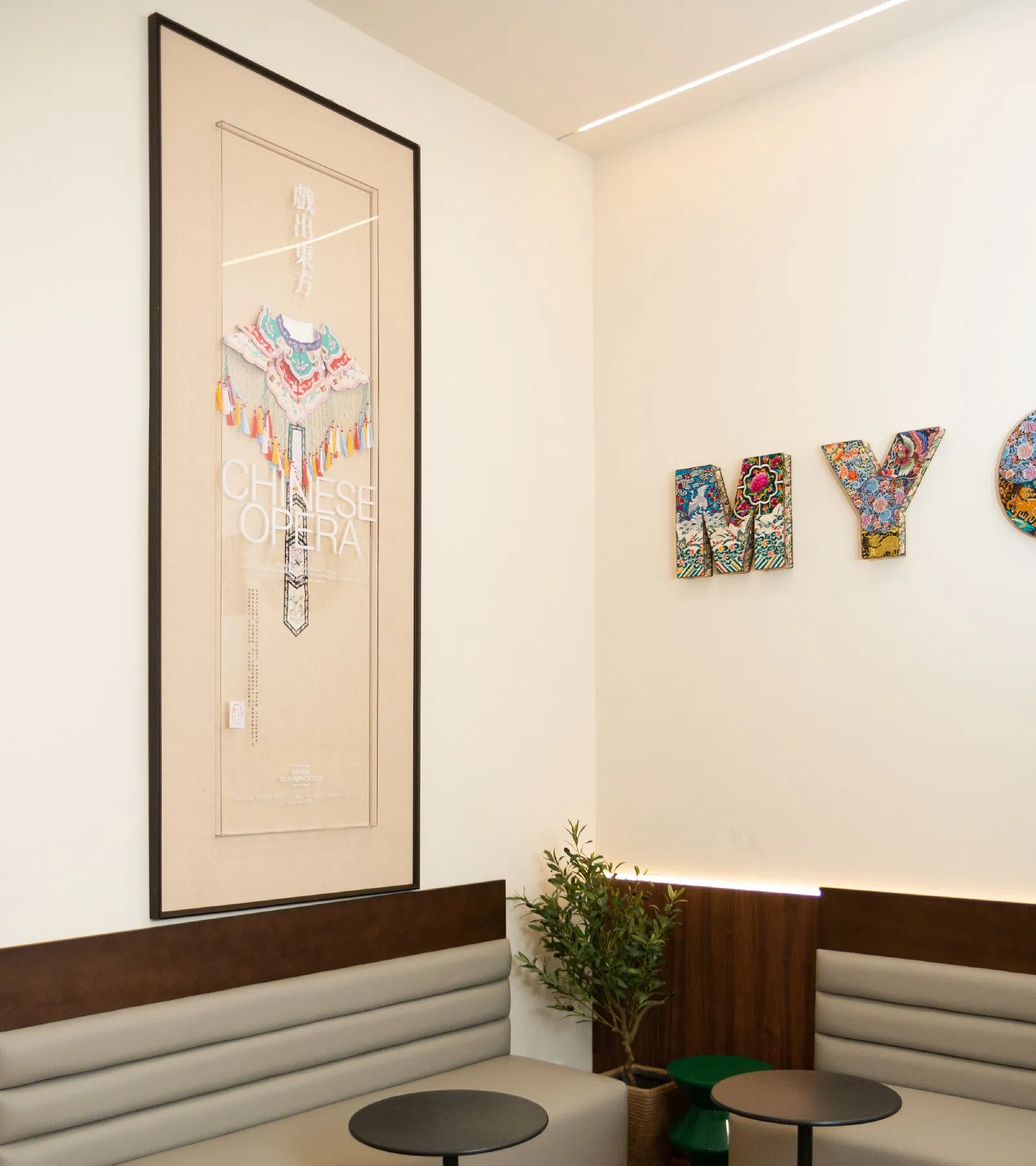 A framed Chinese-opera artwork above banquette seating