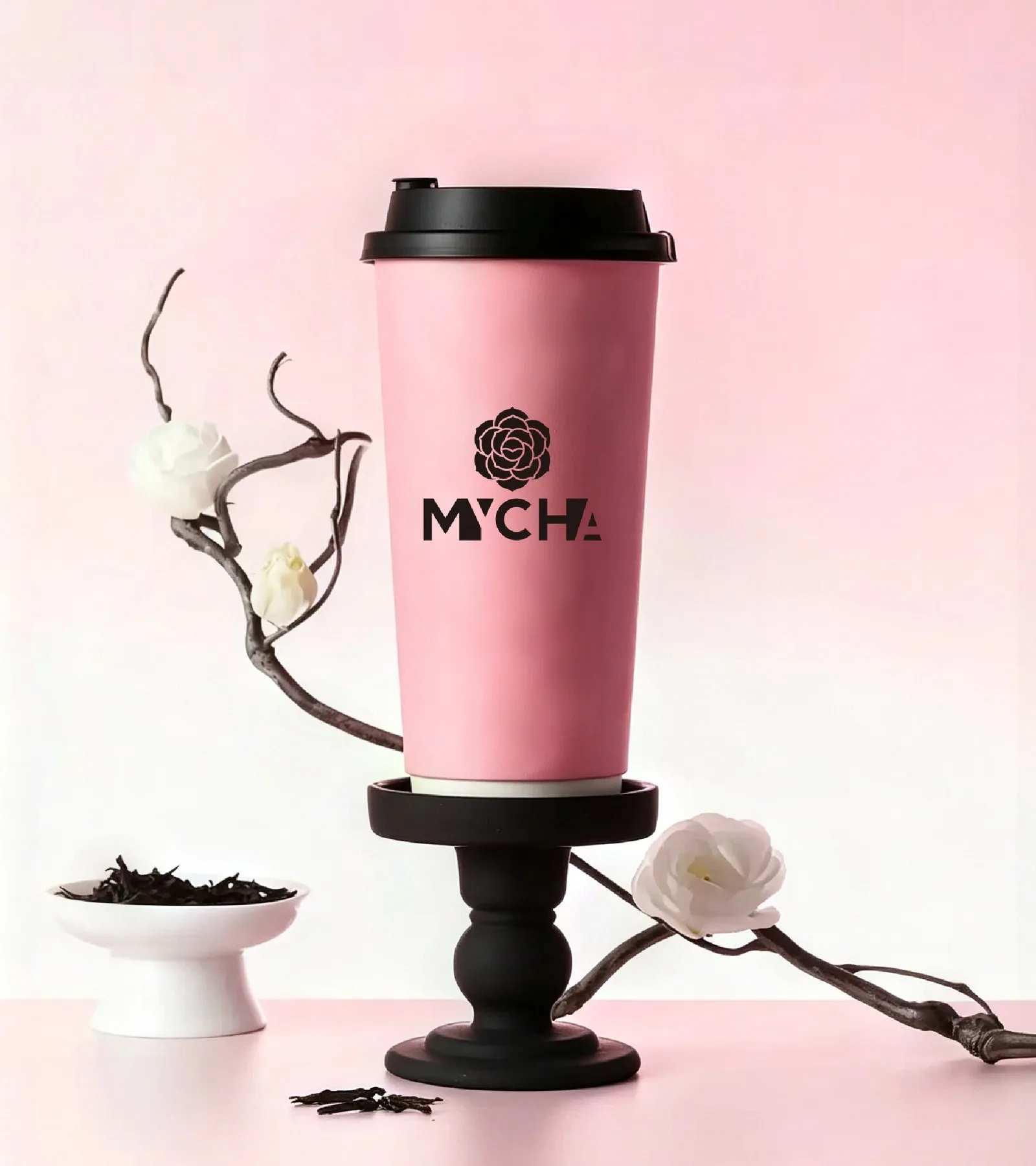 A pink MYCHA cup on a dark pedestal beside a camellia branch