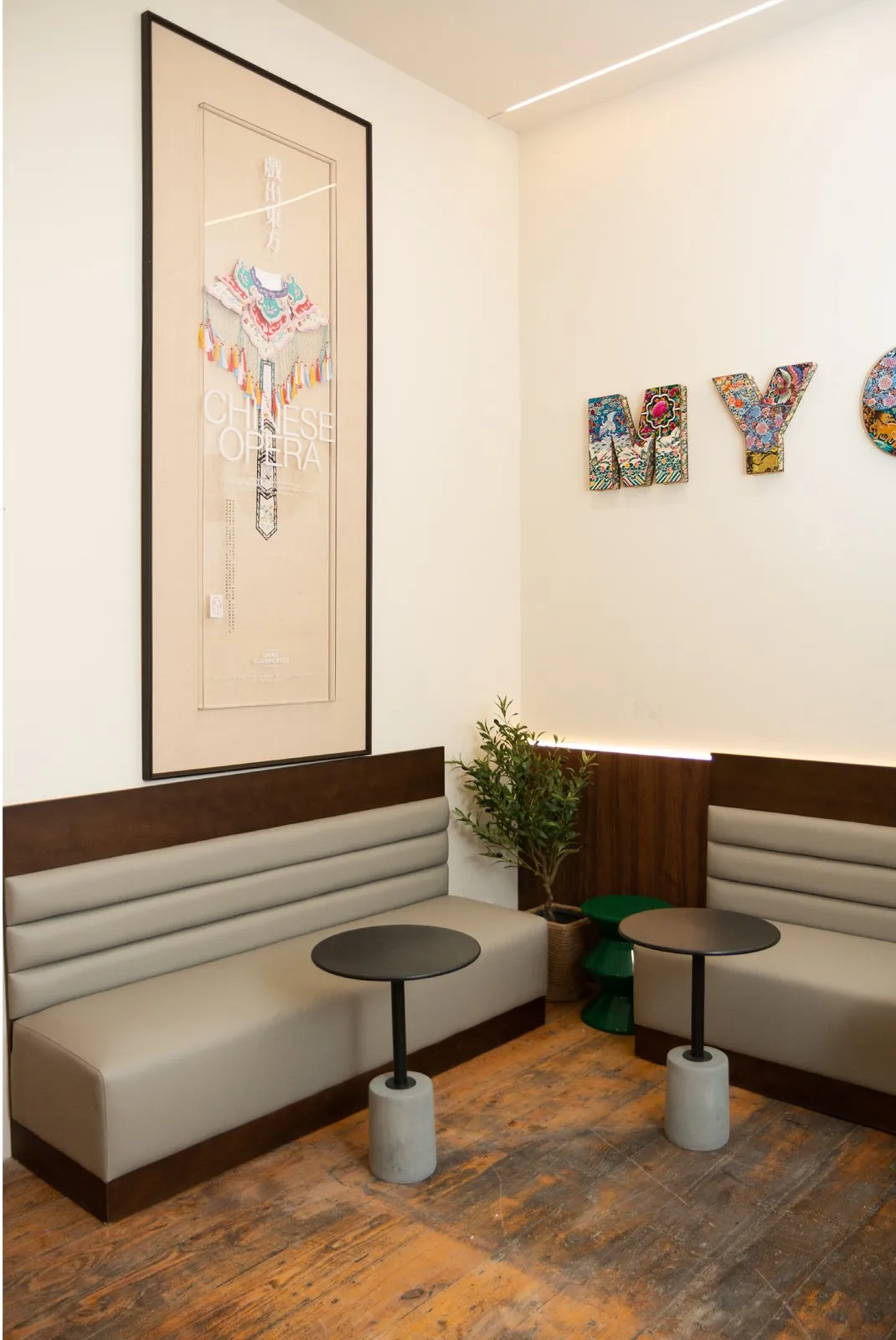 A framed Chinese-opera artwork hanging above banquette seating
